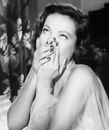 a woman is covering her mouth with her hand in a black and white photo