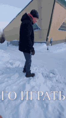 a man in a black jacket is standing in the snow in front of a building that says to igratb