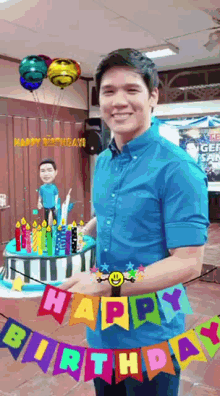 a man in a blue shirt is standing in front of a birthday cake with candles and a happy birthday banner