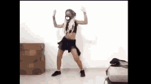 a young girl is dancing in a room with a mask on her face .