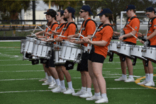 a group of people playing drums with one wearing an orange shirt that says ' a ' on it