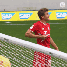 a man in a red shirt is standing on a soccer field in front of a sign that says sap