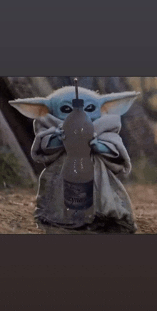 the baby yoda is holding a bottle of water with a straw in his mouth .