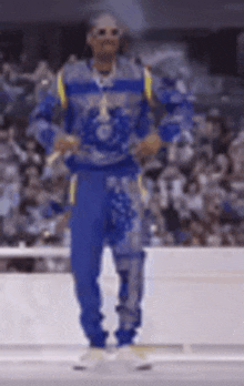 a man in a blue and yellow outfit is dancing in front of a crowd of people .