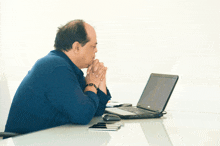 a man sits at a desk with a dell laptop