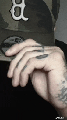 a close up of a person 's hand with a tattoo of the letter b on it