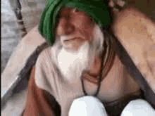 an elderly man with a beard and a green turban is holding a bucket of eggs .