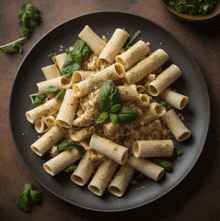 a black plate topped with pasta and basil on a wooden table