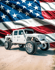 a white jeep is parked in front of a large american flag