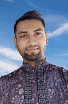 a man with a beard is wearing a purple shirt with a pattern on it