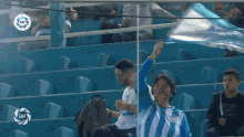 a boy in a blue and white striped shirt holds up a flag in a stadium with a saf logo