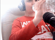 a person wearing a red shirt that says ' w ' on it drinking from a glass