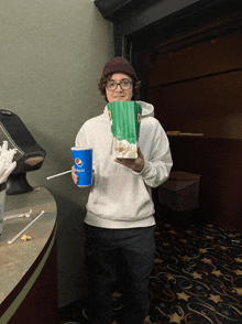 a person holding a bag of popcorn and a blue pepsi cup