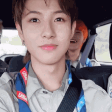 a young man is sitting in the back seat of a car wearing a usa lanyard around his neck .