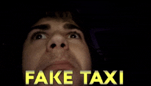 a close up of a man looking up at the words fake taxi