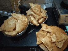 a bowl of chips sits on a counter next to a bowl of fried food