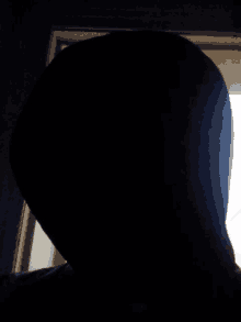 a silhouette of a person 's head is shown in the dark