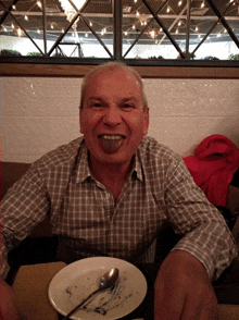 a man in a plaid shirt is sitting at a table with a plate and spoon