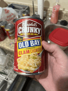 a person is holding a can of campbell 's chunky clam chowder