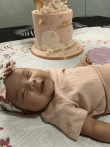 a baby is laying in front of a cake that says happy christening on it