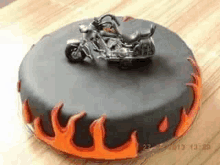 a black cake with a motorcycle on top and flames around it