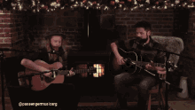 two men singing and playing guitars in front of a fireplace with the hashtag passengermusic.carg