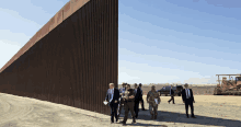 a group of people walking in front of a wall