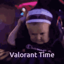 a baby wearing headphones and a headband with the words `` valorant time '' on it .