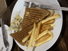 a sandwich and french fries on a white plate with a fork