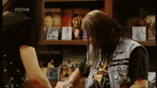 a man in a denim vest is signing a cd in front of a shelf with a mike arrogant cd on it