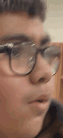 a close up of a man wearing glasses making a face