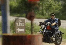 a man is riding a motorcycle down a dirt road next to a sign that says ' a ' on it