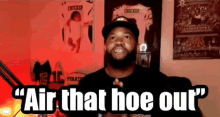 a man with a beard is standing in front of a sign that says " air that hoe out "