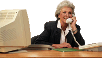 an elderly woman is sitting at a desk talking on a phone