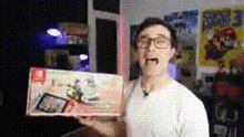 a man wearing glasses is holding a nintendo switch box in his hand .