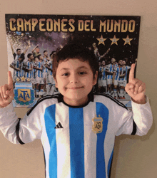 a young boy stands in front of a poster that says ' campeones del mundo ' on it