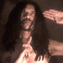 a shirtless man with dreadlocks is making a peace sign with his hands