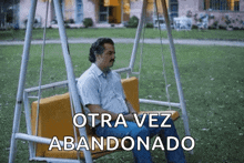 a man sits on a swing with the words otra vez abandonado written below him