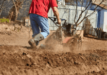 a man in a red shirt is plowing a field with a tractor