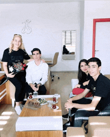 a group of people sitting around a table with a woman holding a bouquet of roses