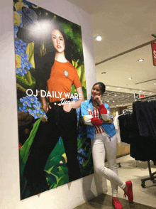 a woman stands in front of a large oj daily ware denim poster