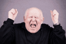 an elderly man is screaming with his mouth open and his fists in the air .