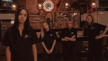 a group of women standing next to each other with their hands on their hips in front of a clock .