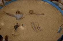 a man and a woman are laying in a pool of sand .