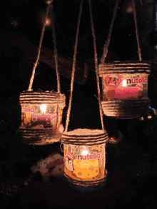 three candles made out of nutella cans are hanging from a rope