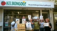 a group of people are holding up signs in front of a store called kelbongoo