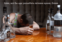 a man laying on a table with bottles of alcohol including a bottle of jack daniel 's