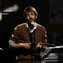 a man sings into a microphone while holding a guitar in front of a sign that says television de catalu