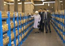 queen elizabeth ii is standing in a warehouse with men