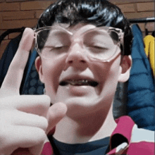 a boy wearing glasses is giving a thumbs up